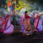 Kolkata, West Bengal, India - 3rd October 2017 : Bengali Hindu ladies dressed in red and white Saris, traditional Indian dress, are dancing with holy smoke at Durga Puja carnival on Red Road at night.